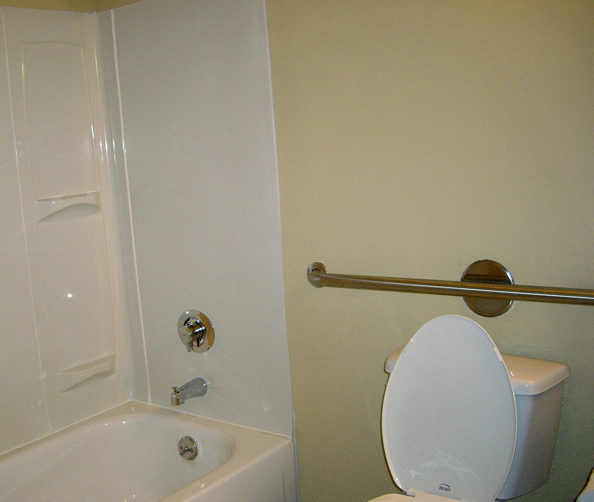 A horizontal grab bar beside a toilet in a bathroom.
